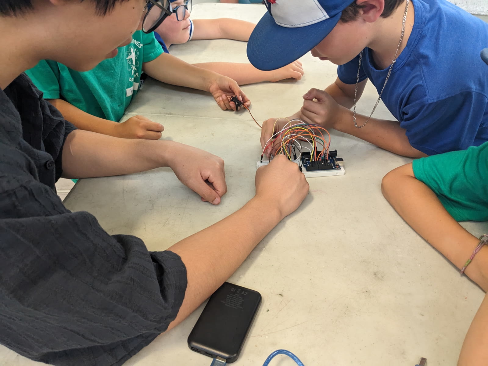 A WLMAC Robotics mentor helping campers connect an Arduino and jumper wires at Human Moves Sports Camp